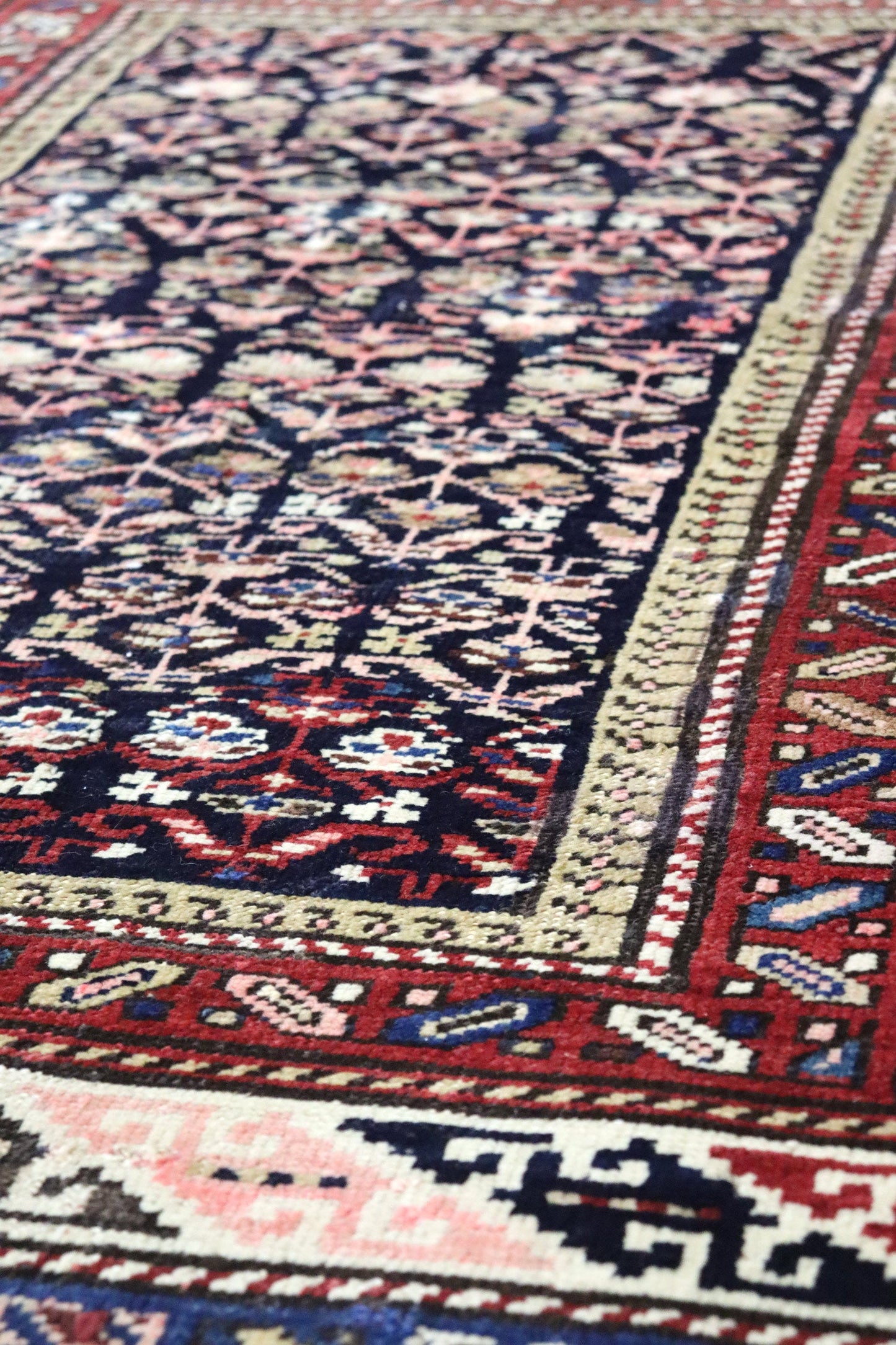 Handwoven tribal rug detail, showcasing intricate floral patterns in deep reds, blues, and creams.

