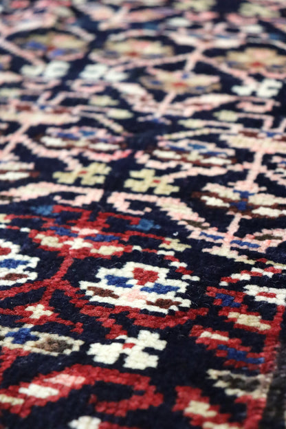 Close-up of a richly colored antique rug with intricate handwoven details.
