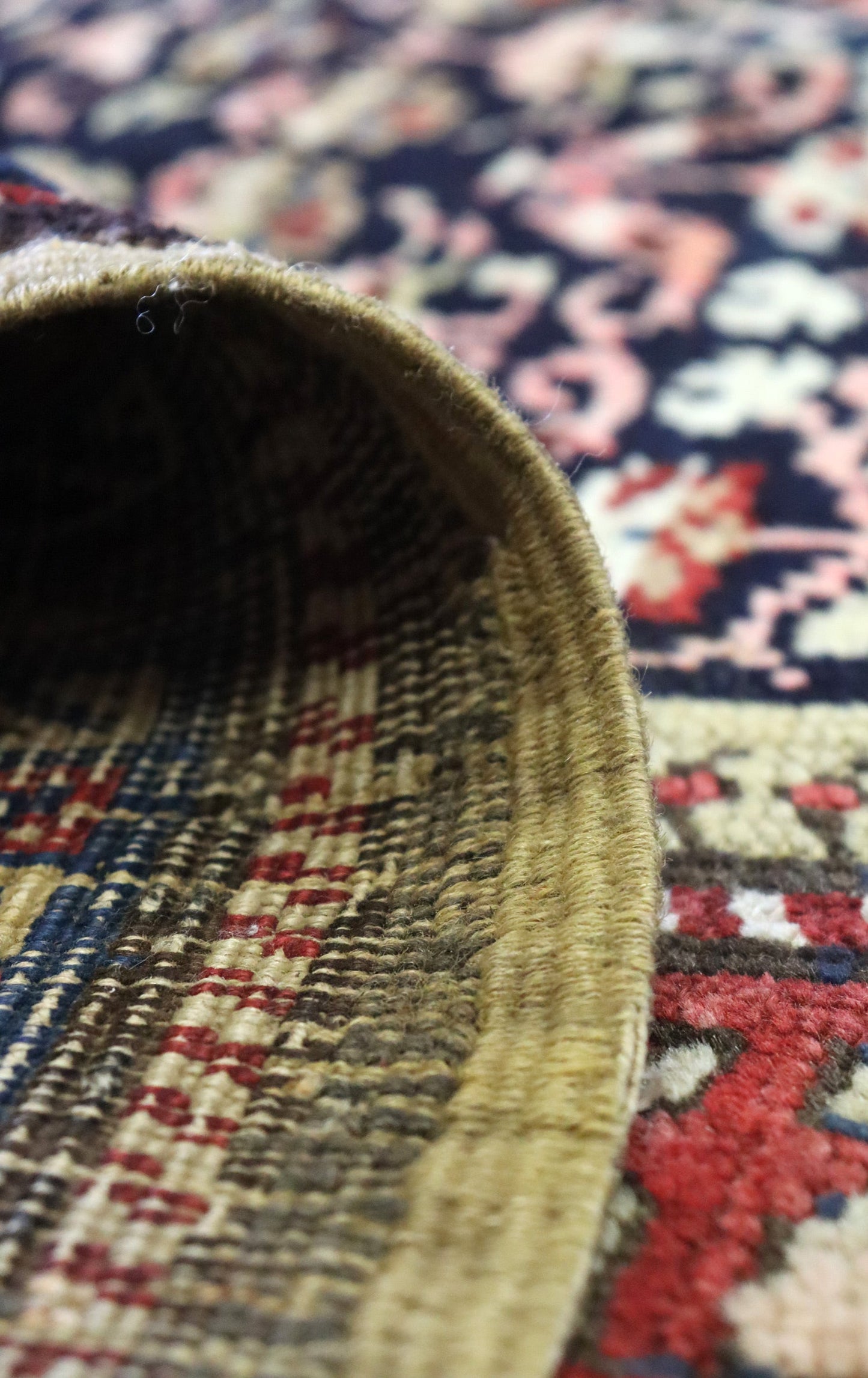 Close-up of antique rug's handwoven edge, showcasing its intricate details and rich, earthy tones.
